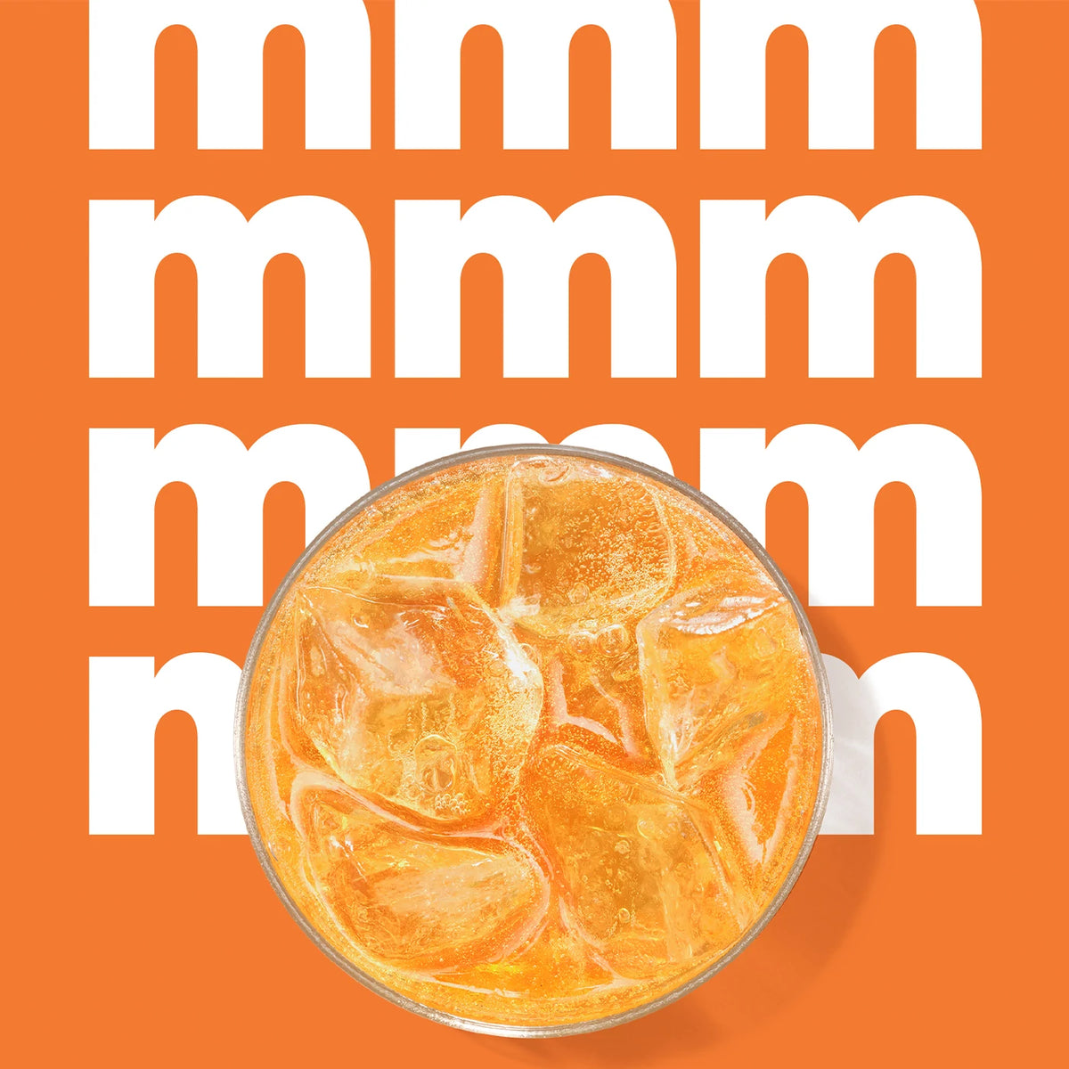 Orange sparkling drink over ice on an orange background with the word “mmm”
