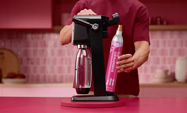 Person attaching a pink Sodastream CO2 cylinder to a sparkling water maker