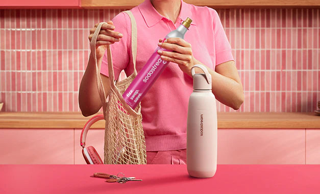 Person packing a pink Sodastream CO2 cylinder into a mesh shopping bag
