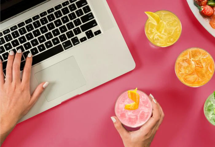 Person using a laptop next to colourful sparkling drinks