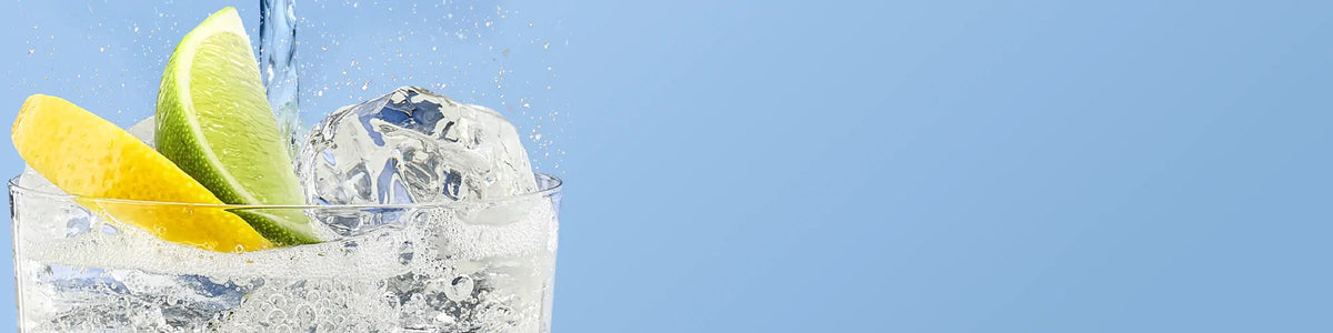 Glass of sparkling water with ice, lemon and lime on a blue background