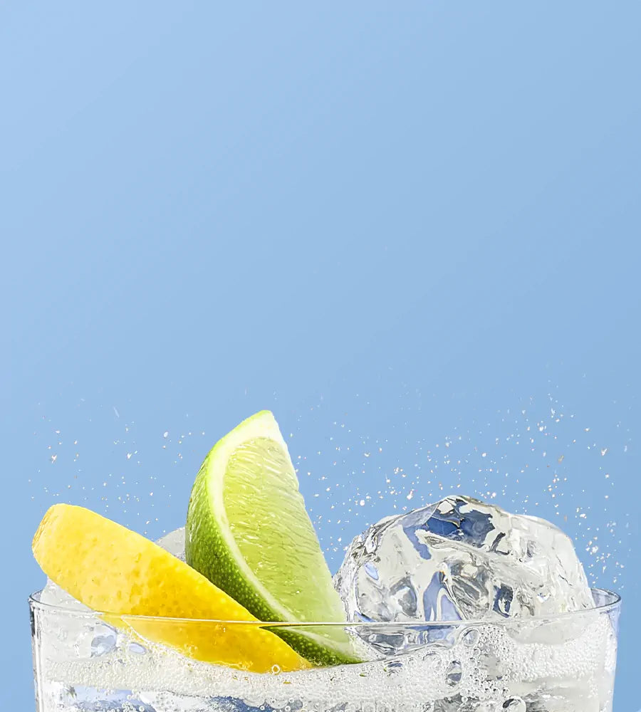 Glass of sparkling water with ice, lemon and lime on a blue background