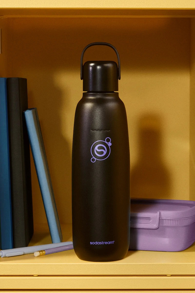 Sodastream Fizz & Go Black bottle on a shelf beside books and a lunch box