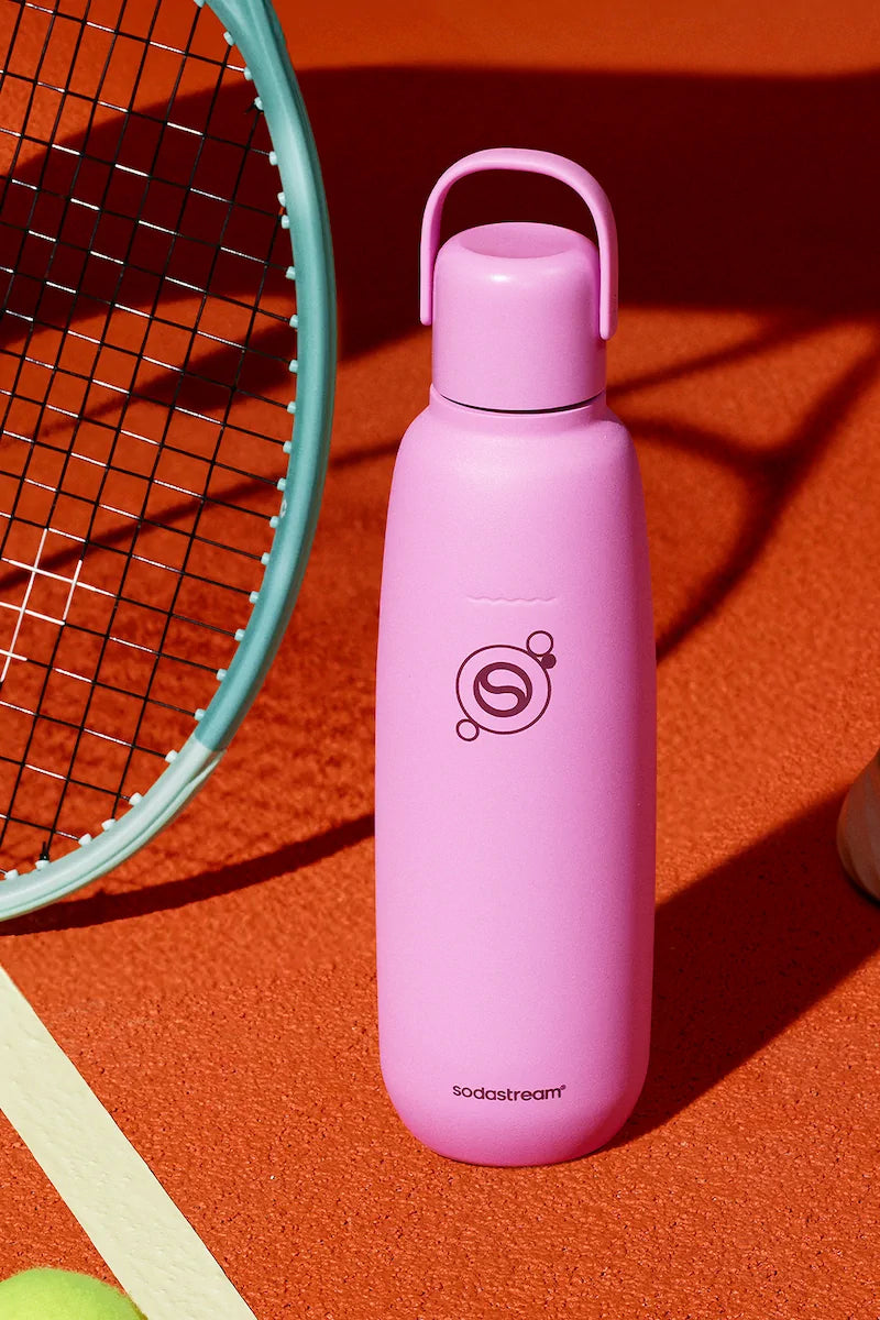 Sodastream Fizz & Go Guava (pink) bottle on a tennis court beside a racket