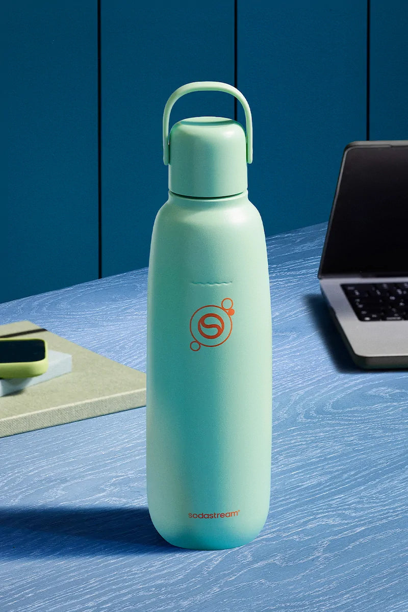 Sodastream Fizz & Go Mint bottle on a blue desk beside a laptop