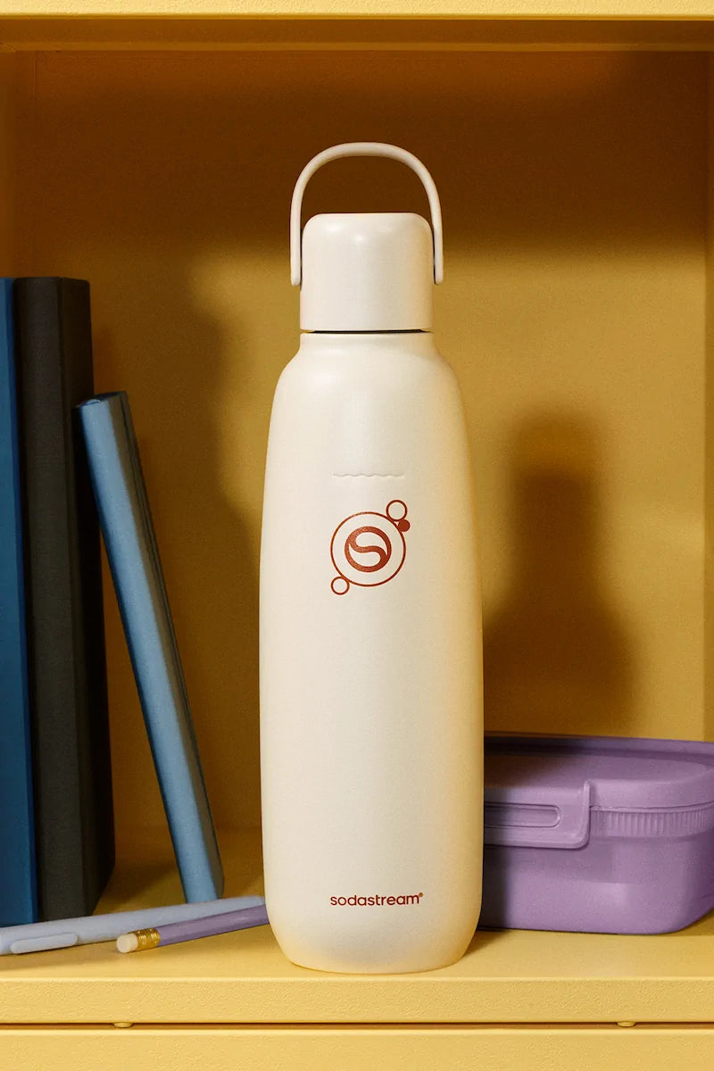 Sodastream Fizz & Go Sand bottle on a shelf beside books and a lunch box
