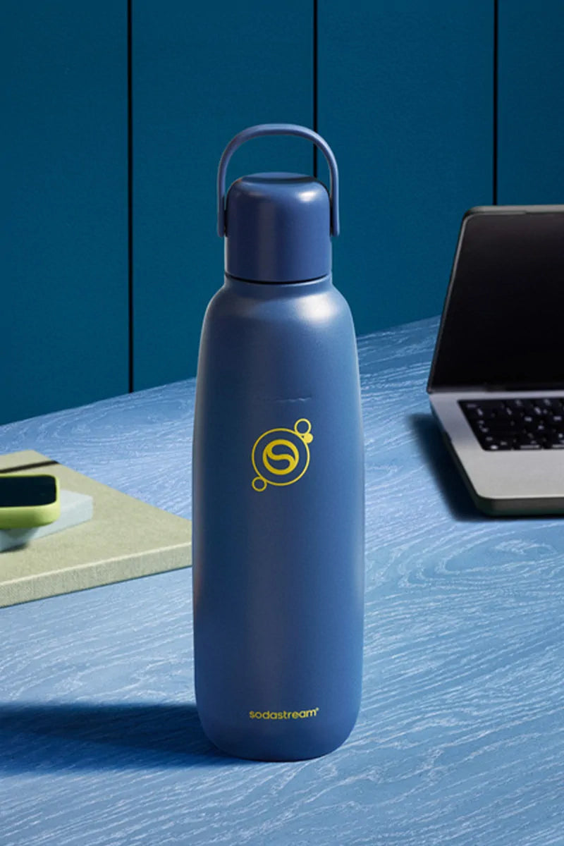 Sodastream Fizz & Go Storm (navy blue) bottle on a blue desk beside a laptop