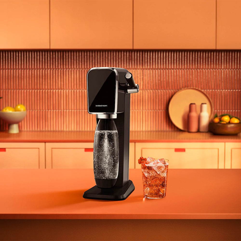 Black Sodastream ART sparkling water maker and an iced drink on a kitchen counter